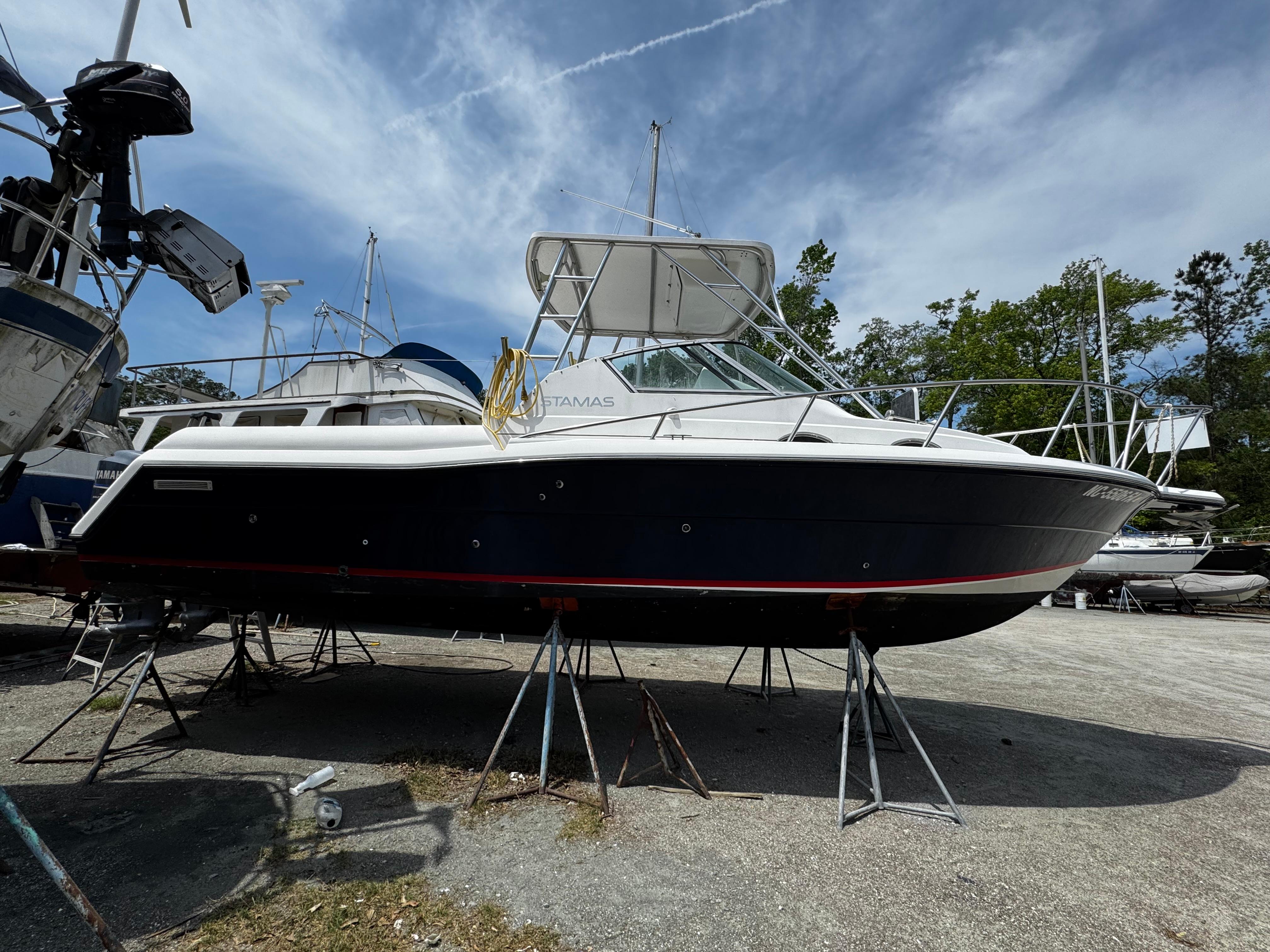 2001 Stamas 310 Express boat on stands, under a partly cloudy sky.