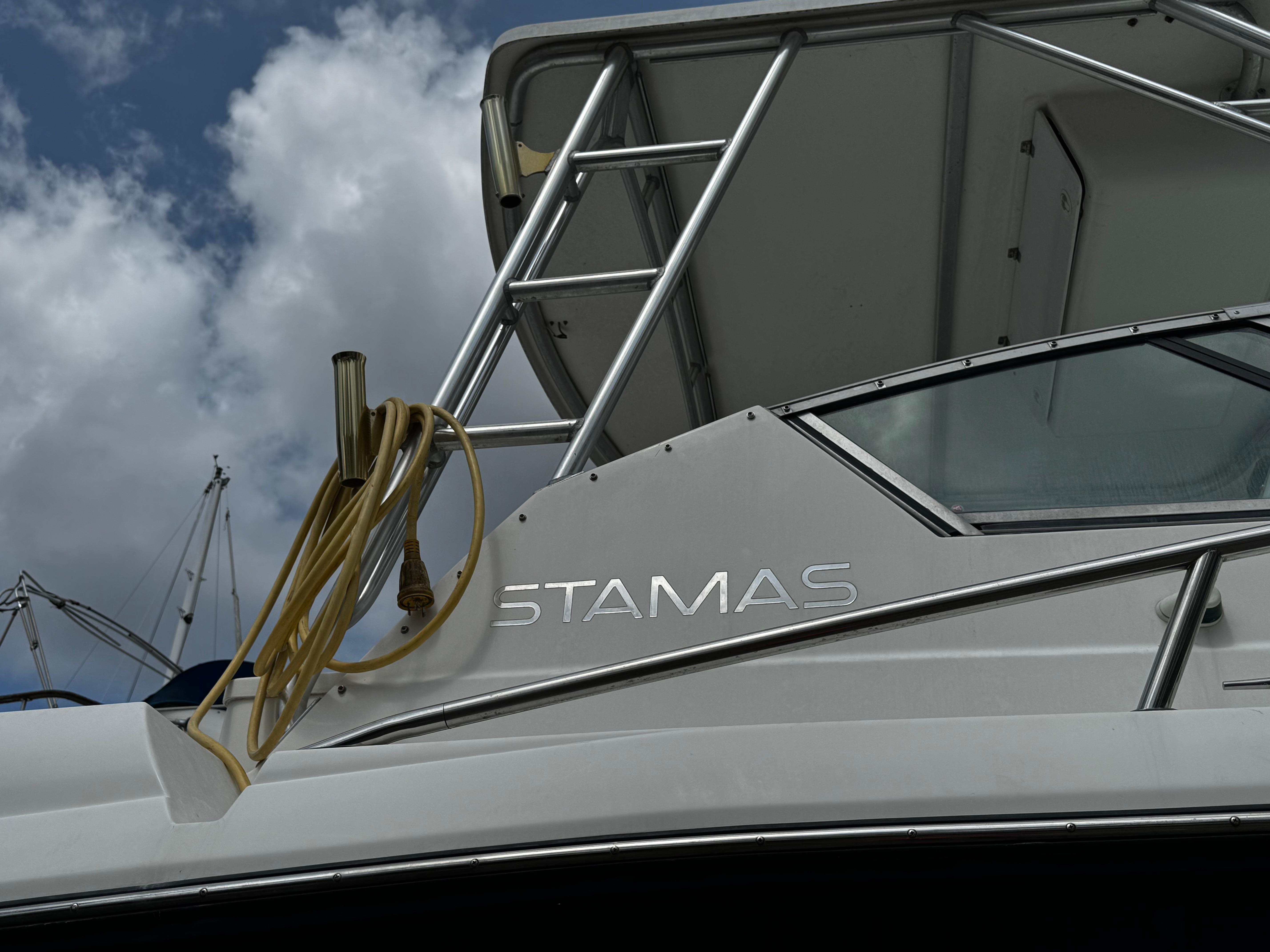 2001 Stamas 310 Express boat with visible name and railing against cloudy sky.