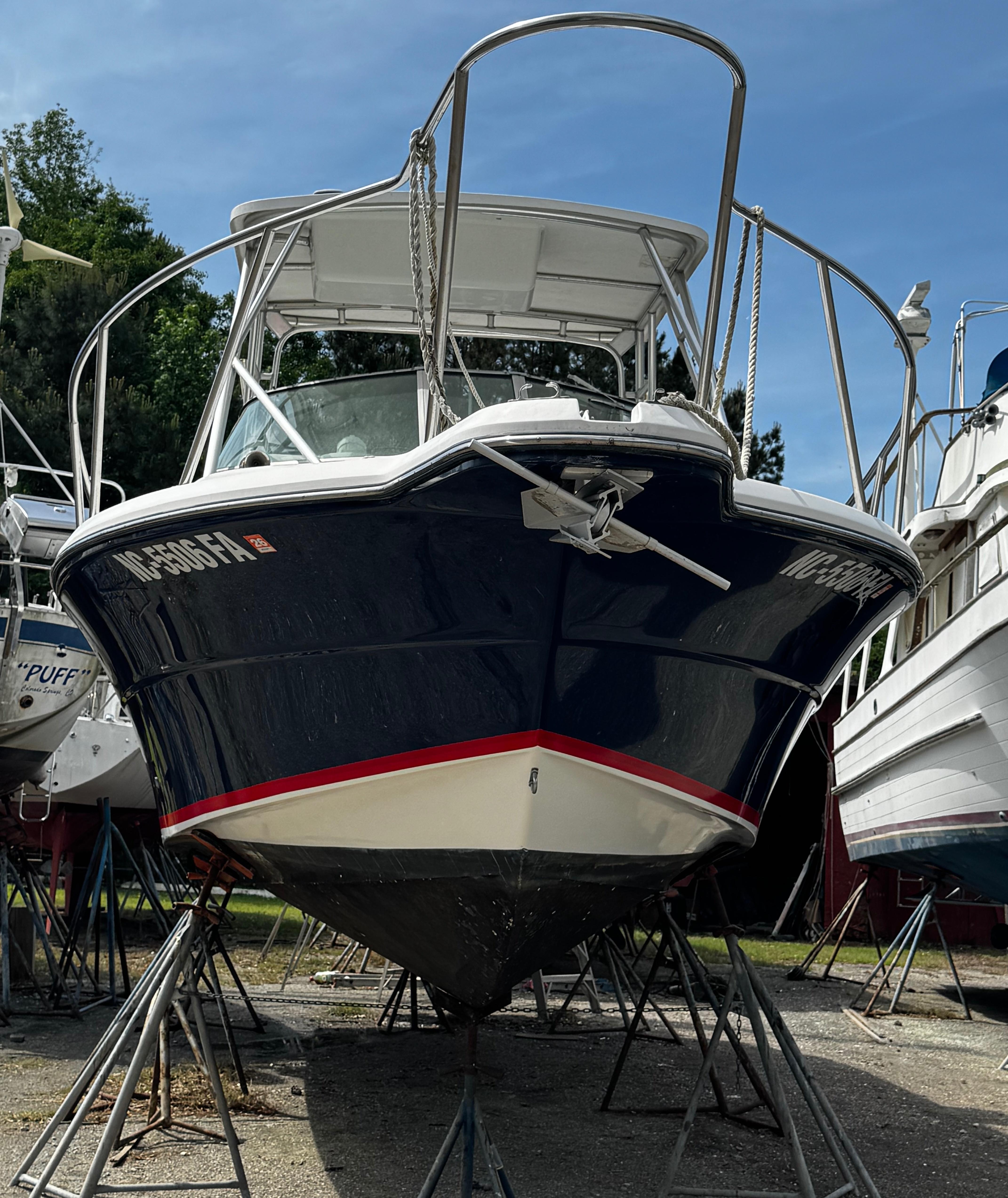 2001 Stamas 310 Express boat on stands, blue hull, white deck, sunny day.
