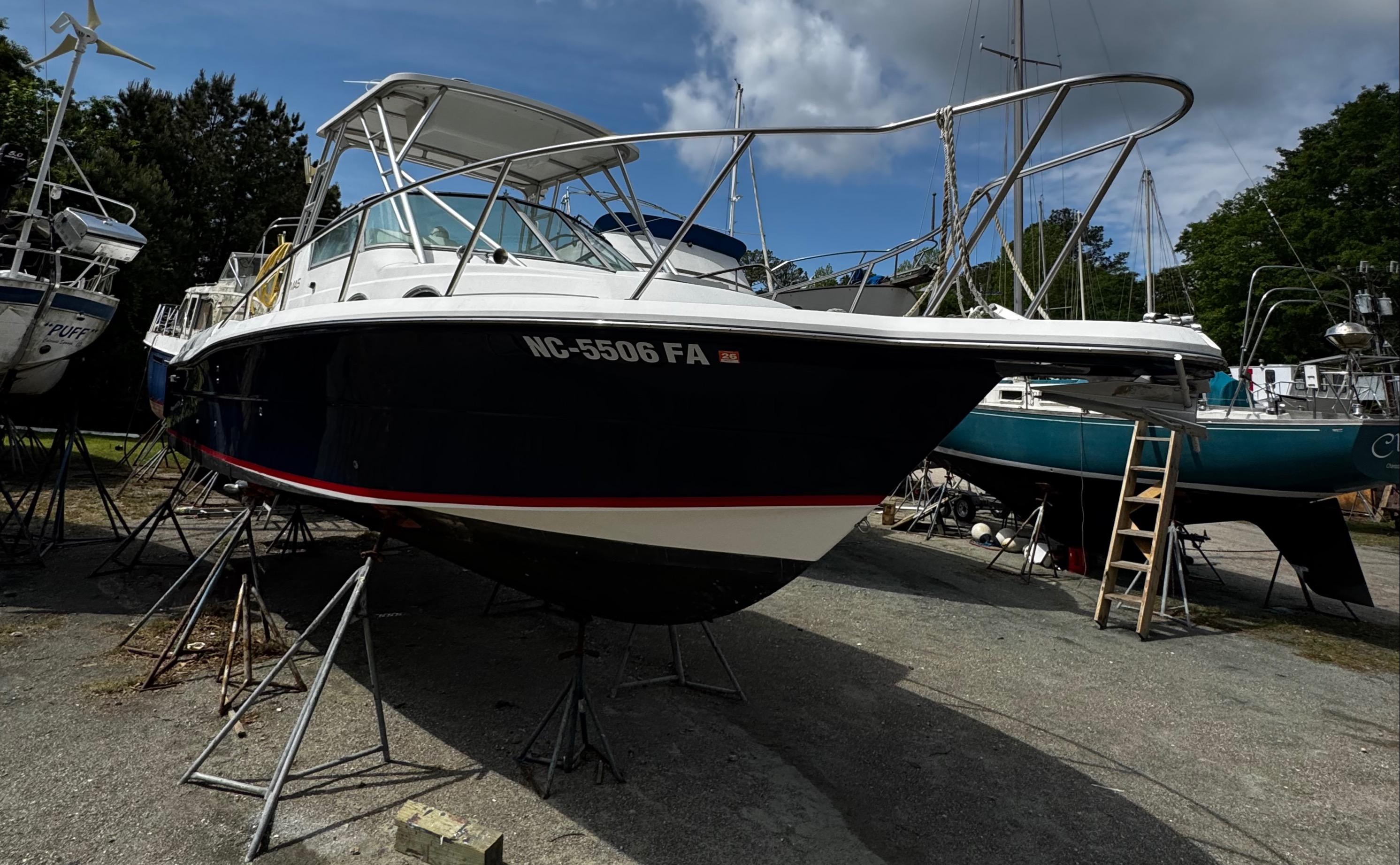 2001 Stamas 310 Express boat on stands, outdoor storage, clear sky background.