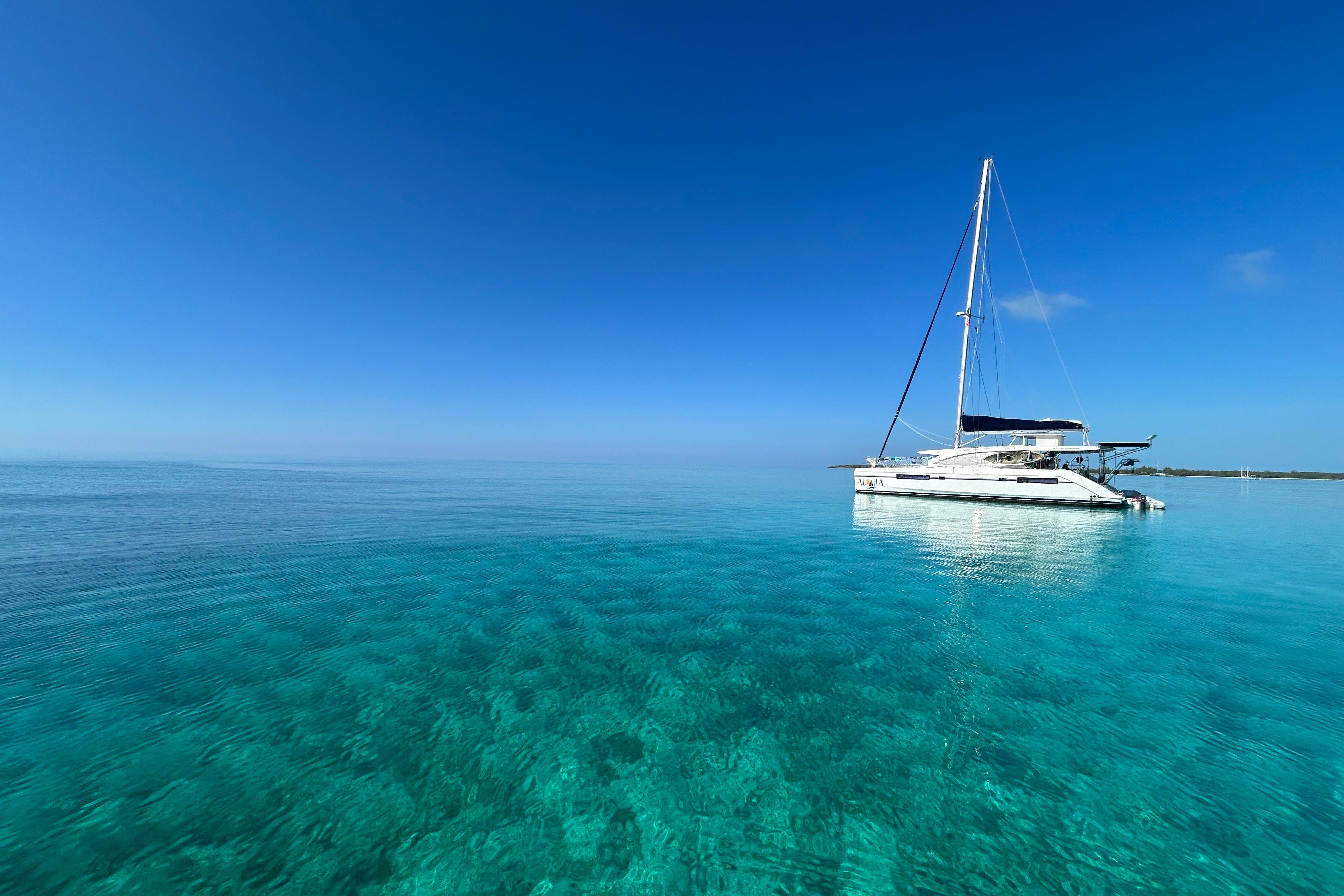 Sailing catamaran Leopard 48 on clear turquoise water, under a bright blue sky.