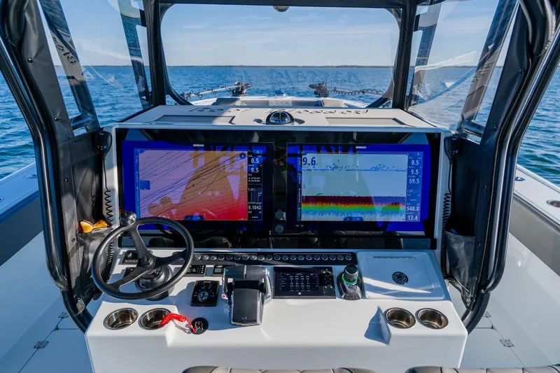 Reel Blessed Yacht Photos Pics Freeman 42LR 2025 boat dashboard with navigation screens and steering wheel on open water.