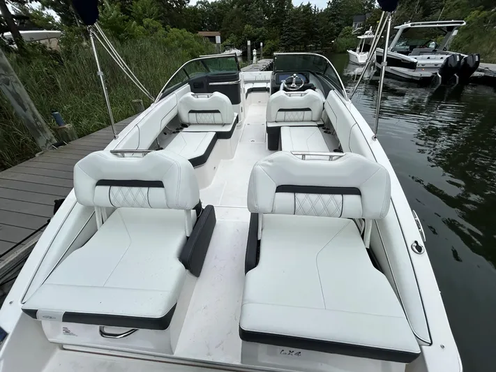  Yacht Photos Pics 2026 Regal LX4 boat with white seating, docked by a wooden pier, surrounded by greenery.
