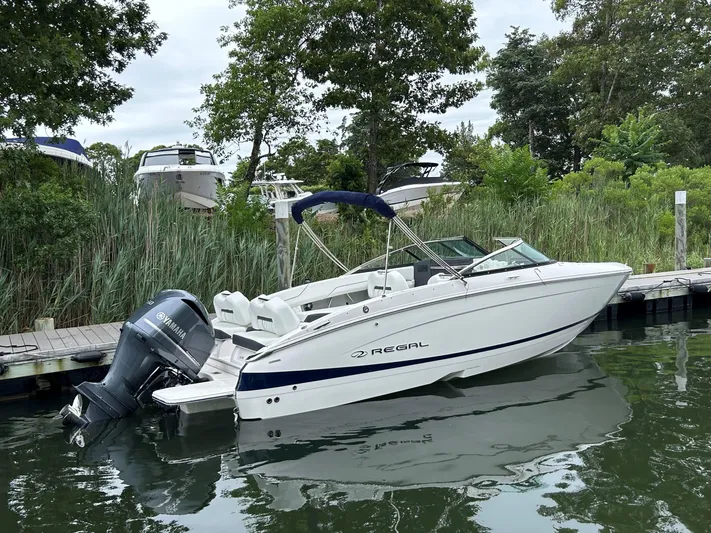  Yacht Photos Pics 2026 Regal LX4 boat docked by lush greenery and calm waters.