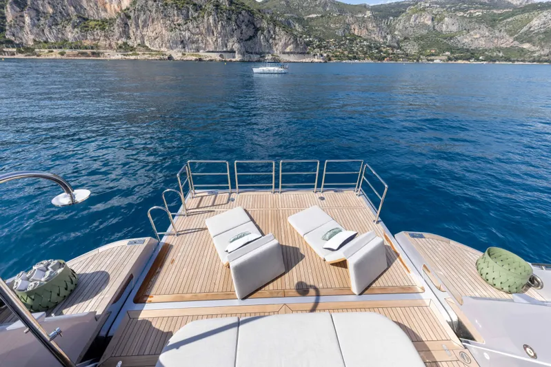 Ocean One Yacht Photos Pics Luxurious Azimut Grande 36M yacht deck with sun loungers, overlooking serene blue waters and rocky coastline.