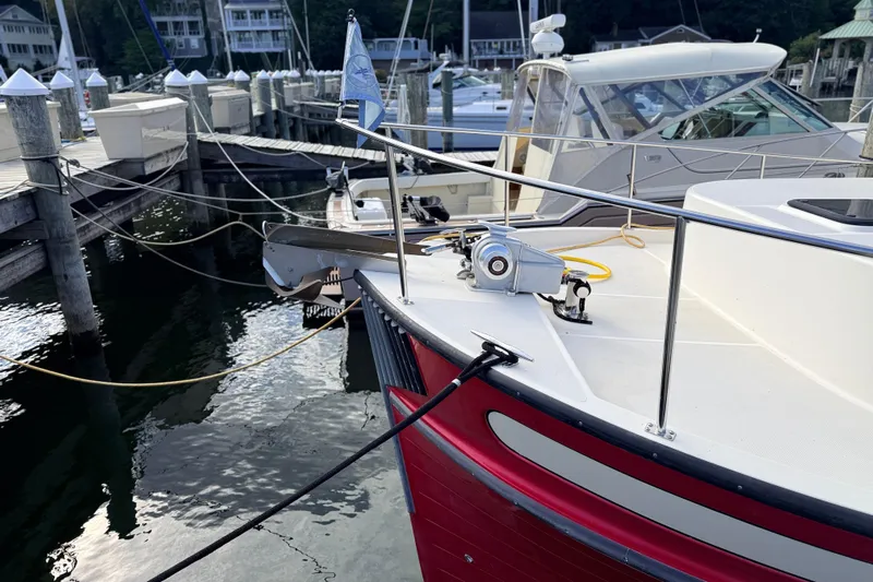 Nomad Yacht Photos Pics Nordic Tug 37 (2000) docked at marina, featuring red hull and white deck.