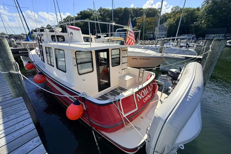 Nomad Yacht Photos Pics Nordic Tug 37, 2000 model, docked with red accents and inflatable dinghy.