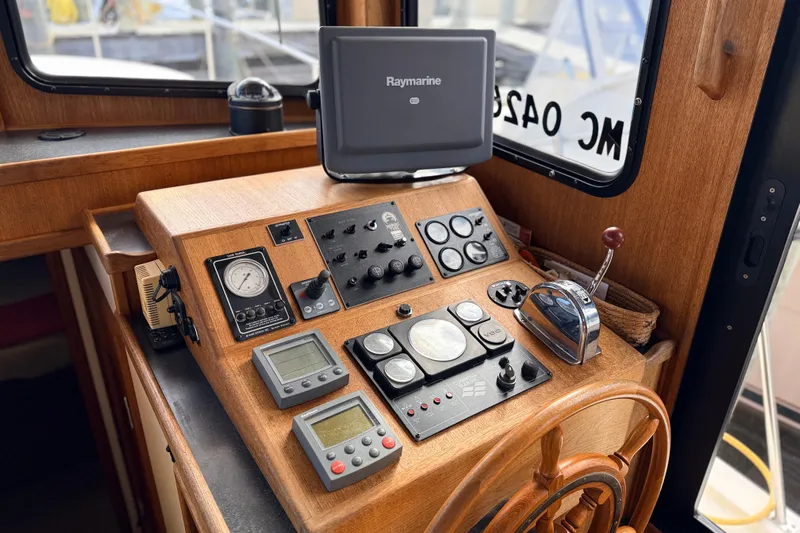 Nomad Yacht Photos Pics Nordic Tug 37 (2000) helm with Raymarine navigation system and classic wooden steering wheel.