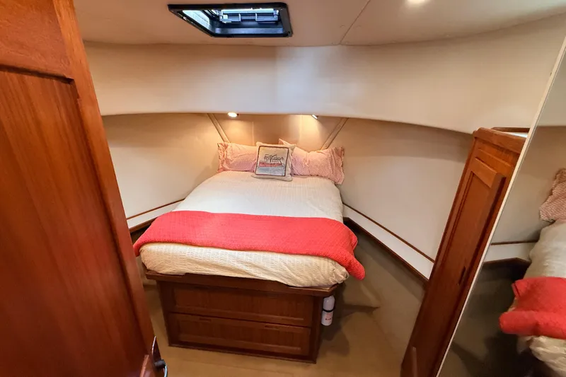 Nomad Yacht Photos Pics Cozy bedroom in 2000 Nordic Tug 37 boat with bed, pillows, and wooden cabinetry.