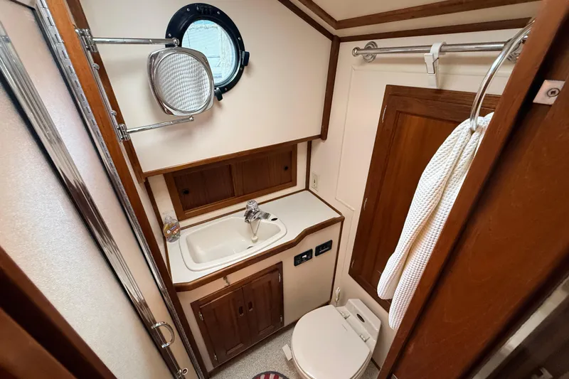 Nomad Yacht Photos Pics Nordic Tug 37 (2000) bathroom with sink, mirror, and toilet in compact marine design.