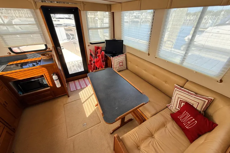Nomad Yacht Photos Pics Interior of 2000 Nordic Tug 37 with cozy seating, table, and kitchenette.