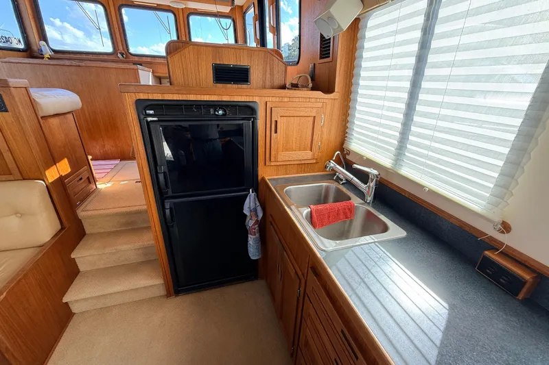 Nomad Yacht Photos Pics Nordic Tug 37 (2000) interior kitchen with wooden cabinetry, sink, and refrigerator.
