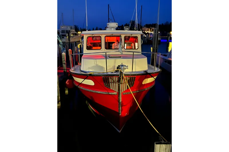 Nomad Yacht Photos Pics Red 2000 Nordic Tug 37 docked at night, illuminated with warm interior lights.