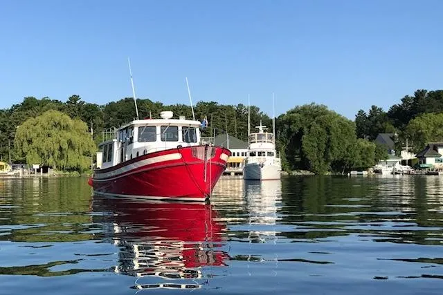 Nomad Yacht Photos Pics Red 2000 Nordic Tug 37 boat on calm water with scenic background.