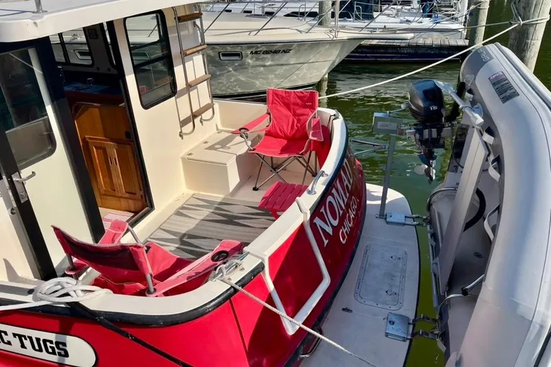 Nomad Yacht Photos Pics Nordic Tug 37, 2000 model, with red chairs on deck, docked at marina.