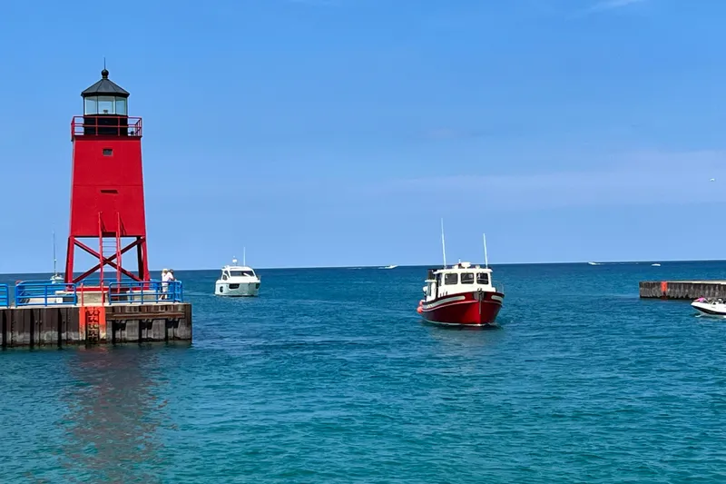 Nomad Yacht Photos Pics Red lighthouse and Nordic Tug 37 boat on clear blue water, 2000 model.