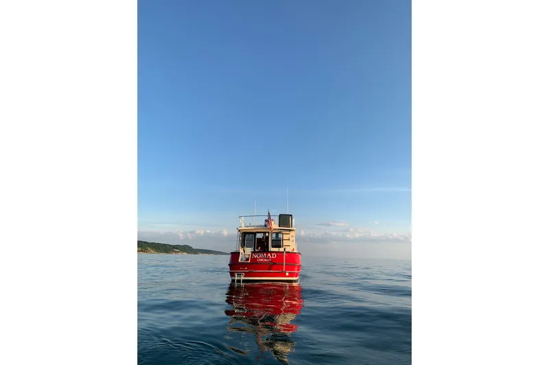 Nomad Yacht Photos Pics 2000 Nordic Tug 37 boat on calm water under clear blue sky.