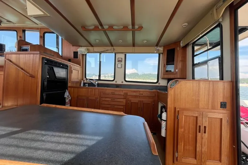 Nomad Yacht Photos Pics Interior of 2000 Nordic Tug 37, featuring wood cabinetry and large windows.