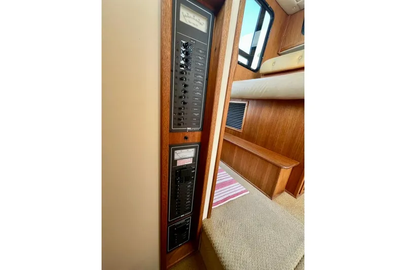 Nomad Yacht Photos Pics Electrical panel inside a 2000 Nordic Tug 37 boat, featuring wood interior and carpeted steps.