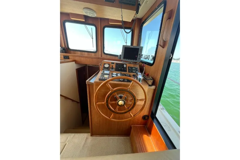Nomad Yacht Photos Pics Interior helm of 2000 Nordic Tug 37 with wooden steering wheel and navigation equipment.