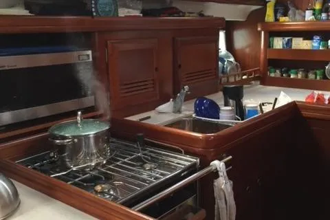 Peregrine Yacht Photos Pics Galley kitchen in 2005 Beneteau 423 yacht with stove, sink, and storage shelves.