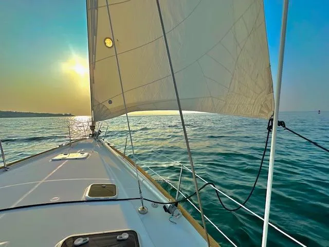 Peregrine Yacht Photos Pics Sailing on a 2005 Beneteau 423 yacht at sunset over calm ocean waters.