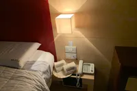 Cozy bedroom with bedside table, lamp, phone, and neatly arranged towels.