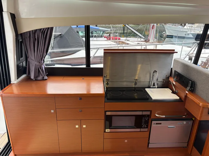  Yacht Photos Pics Modern kitchen interior of 2014 Jeanneau NC 14 yacht with appliances and wood cabinetry.