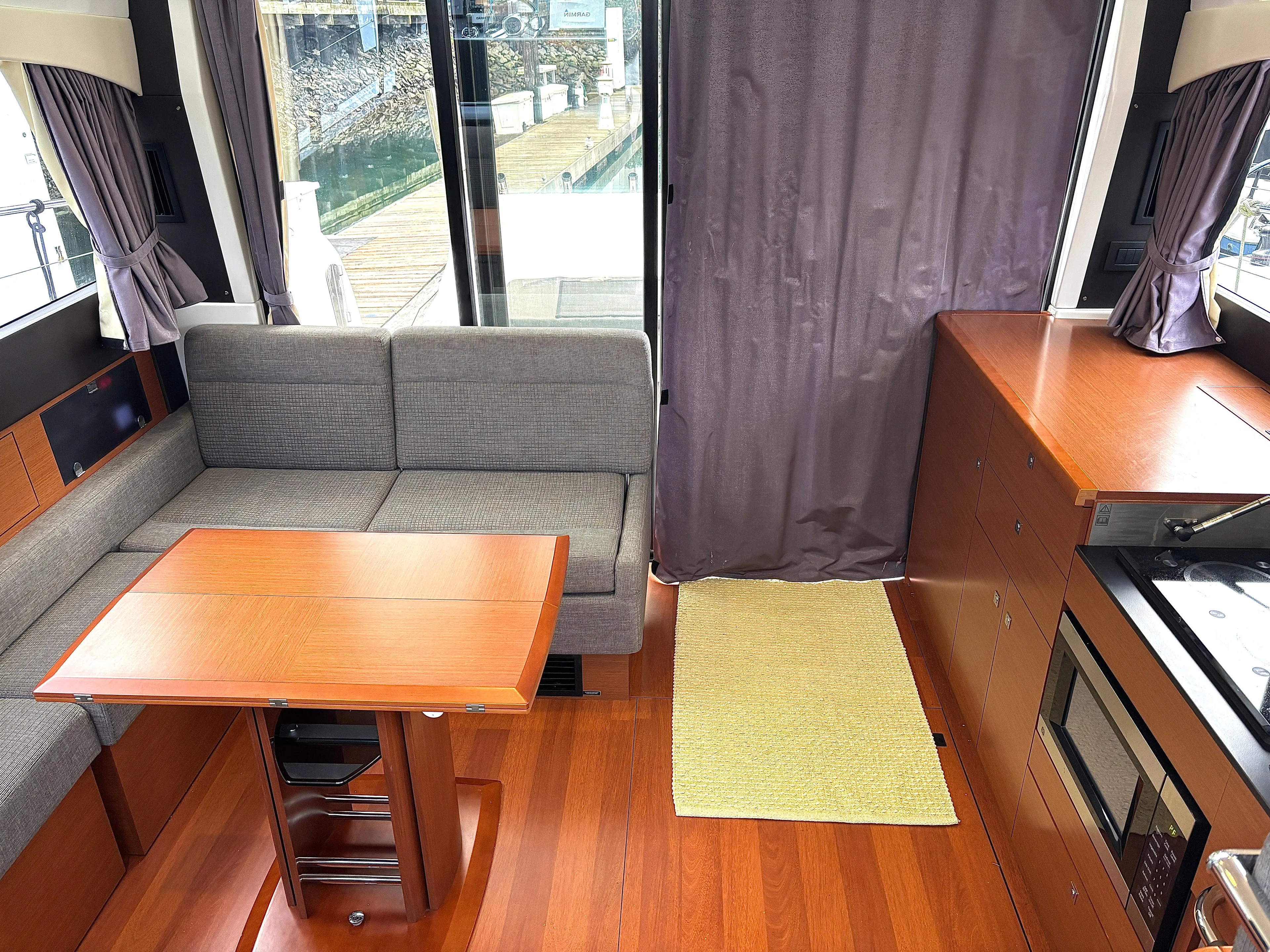  Yacht Photos Pics Interior of 2014 Jeanneau NC 14 yacht with wood flooring and cozy seating area.