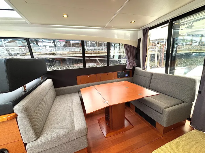  Yacht Photos Pics Interior of 2014 Jeanneau NC 14 yacht with modern seating and wooden table.