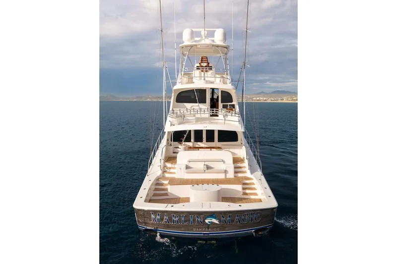 Marlin Magic Yacht Photos Pics 2021 Viking 92 Skybridge yacht on open water, rear view, named "Marlin Magic."