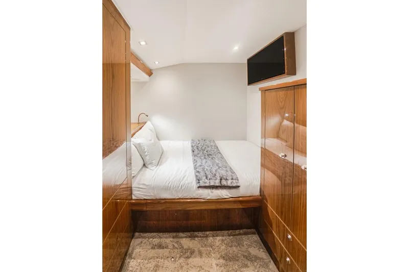 Marlin Magic Yacht Photos Pics Luxurious bedroom interior of 2021 Viking 92 Skybridge yacht with wood cabinetry and TV.