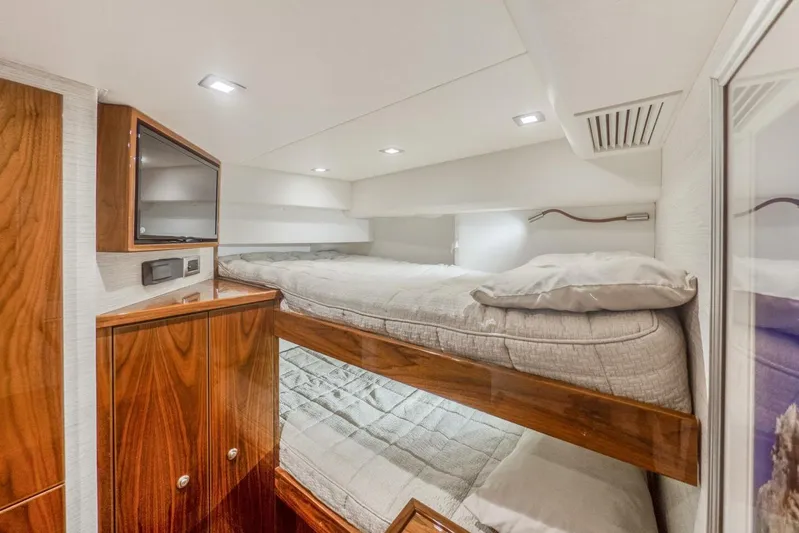 Marlin Magic Yacht Photos Pics Luxurious cabin interior of 2021 Viking 92 Skybridge yacht with bunk beds and wood cabinetry.