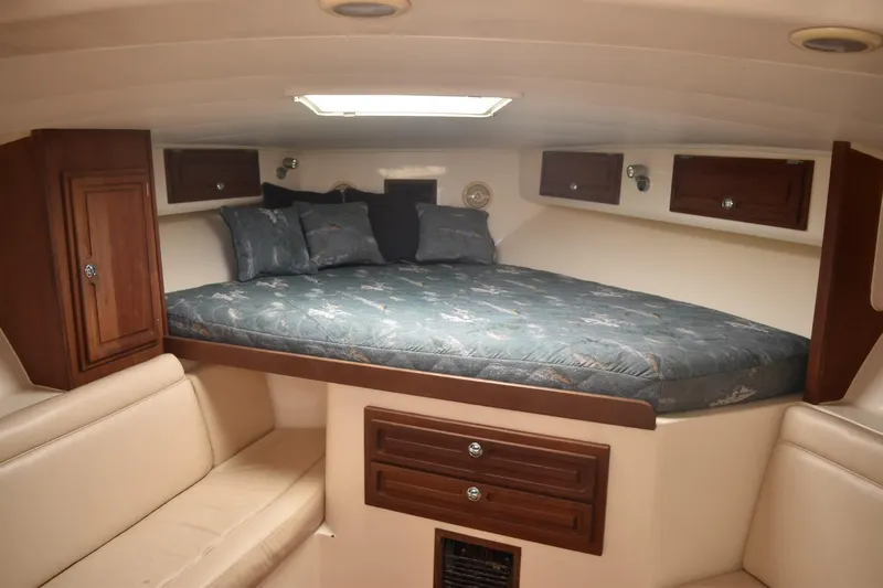 Miss Print Yacht Photos Pics Interior cabin of a 2006 Carolina Classic 32 boat with a cozy bed and wooden cabinets.