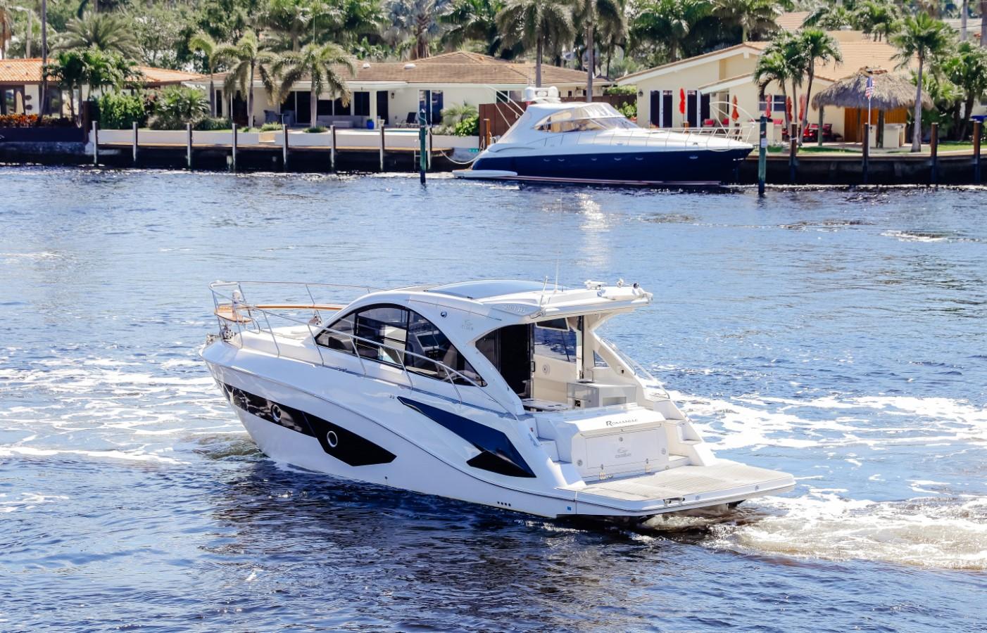 2021 Evolve 400HT yacht cruising on a sunny waterfront with palm trees and houses.