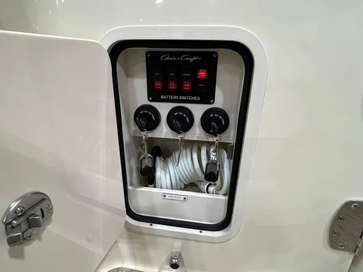  Yacht Photos Pics Battery switches panel on 2023 Chris-Craft Calypso 35 boat, featuring coiled hose storage.