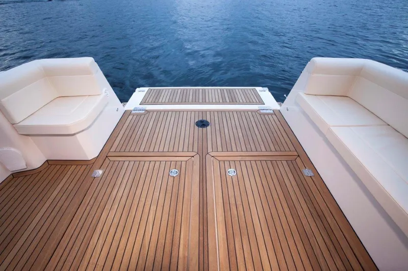 Pastiche Yacht Photos Pics 2019 Greenline Hybrid boat deck with wooden flooring and cushioned seating, overlooking calm water.