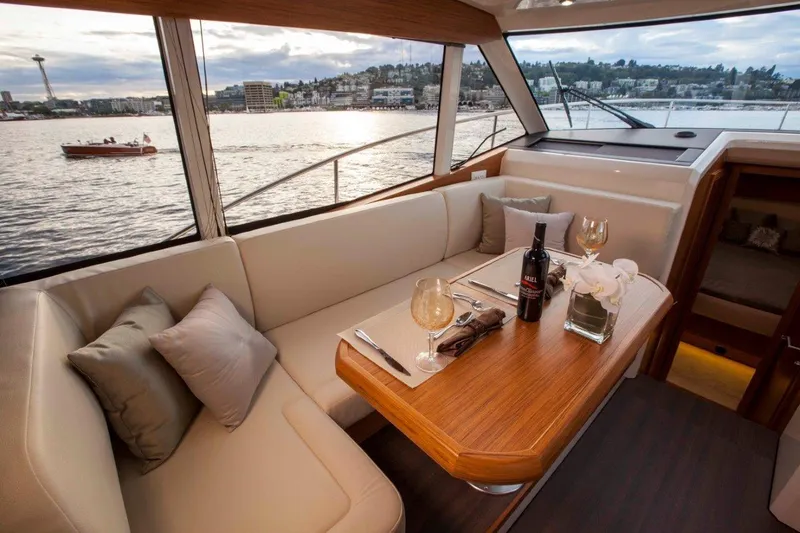 Pastiche Yacht Photos Pics Luxurious interior of 2019 Greenline Hybrid yacht with dining area overlooking scenic waterfront.