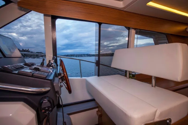 Pastiche Yacht Photos Pics Interior of 2019 Greenline Hybrid boat with steering wheel and seating, overlooking water.