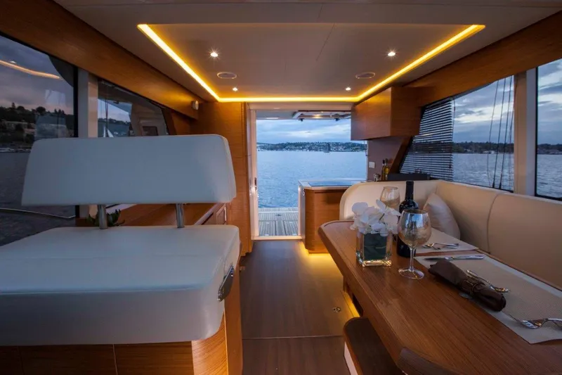 Pastiche Yacht Photos Pics Luxurious interior of a 2019 Greenline Hybrid yacht with elegant dining setup and scenic water view.