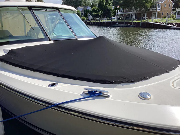  Yacht Photos Pics 2017 Pursuit DC 325 Dual Console boat with black cover, docked by a waterfront home.