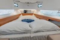 Luxurious cabin interior of 2022 Nimbus T11 boat with comfortable bedding and ocean view.