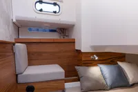 Cozy cabin interior of 2022 Nimbus T11 boat with wooden accents and cushions.