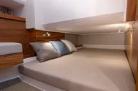 Luxurious cabin interior of 2022 Nimbus T11 boat with cozy bedding and wooden accents.