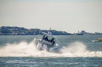 Nimbus T11 boat navigating waves, 2022 model, with rocky coastline in the background.