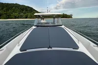 2022 Nimbus T11 boat on water near lush island, featuring spacious deck and sleek design.