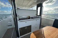 Outdoor kitchen on a 2022 Nimbus T11 yacht, featuring a sink and stove, with ocean view.