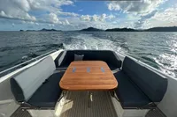 Sleek Nimbus T11 boat interior with wooden table, ocean view, and island backdrop.