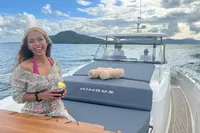 Smiling woman enjoying a drink on a 2022 Nimbus T11 yacht, cruising on open water.