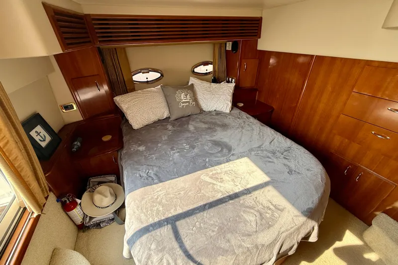 One Last Time II Yacht Photos Pics Luxurious bedroom in 2004 Carver 444 Cockpit Motor Yacht with wood paneling and cozy bedding.